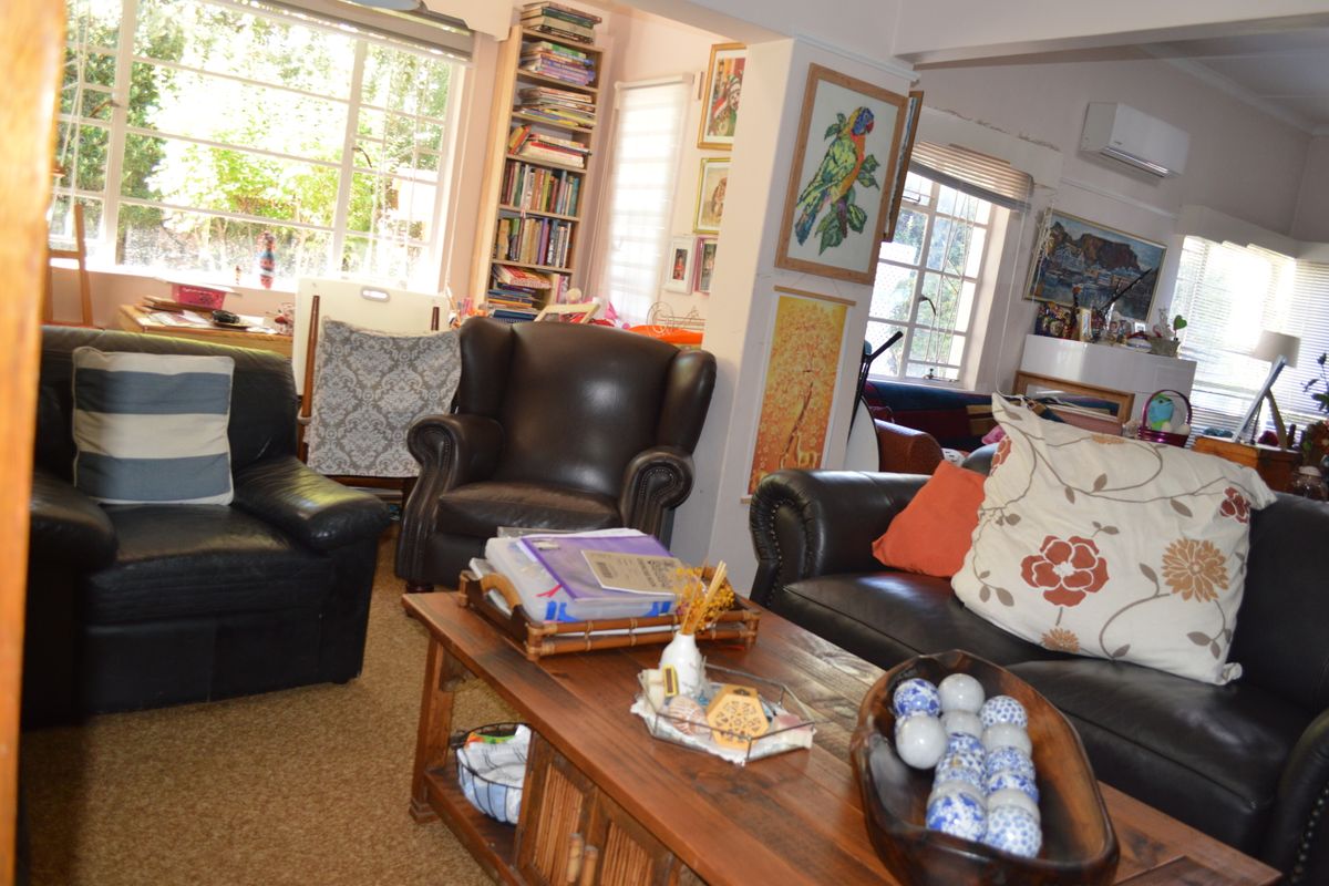 A comfortable living room featuring built-in shelving, a split-system air conditioner, and large windows that provide ample natural light.