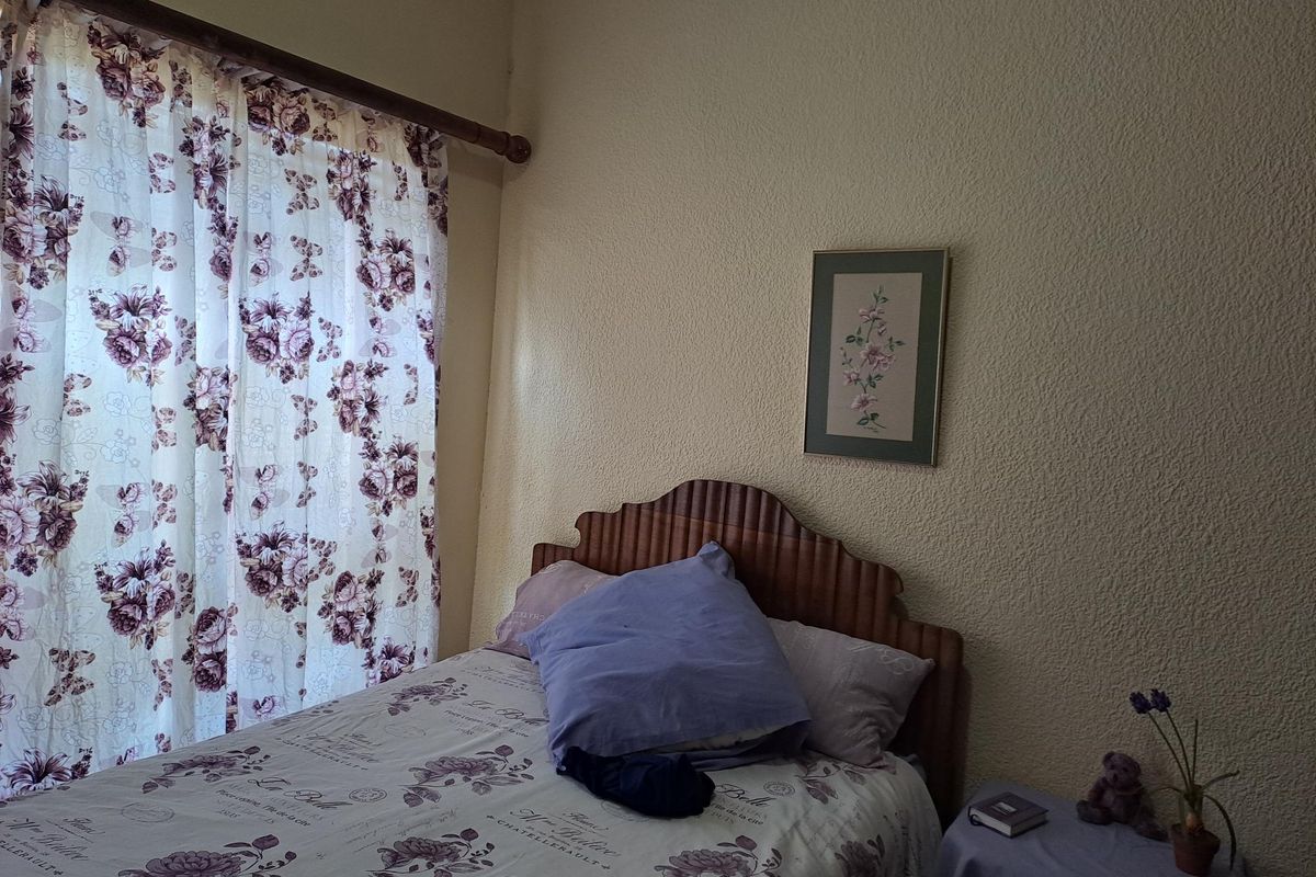 A bedroom featuring textured wall finishes and a window with curtain treatments.