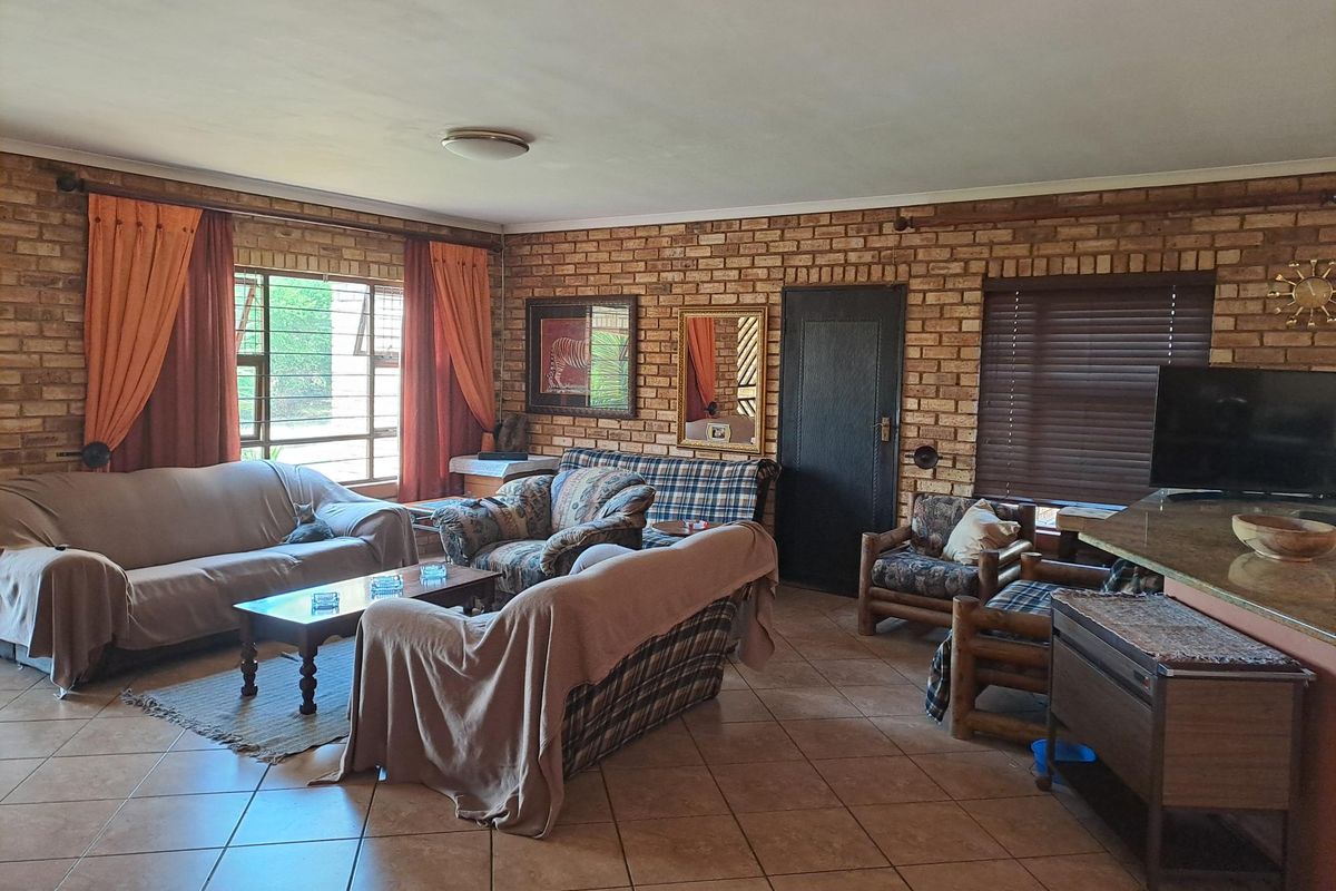 Spacious living area featuring exposed brick walls, tiled flooring, and large windows allowing for natural light.