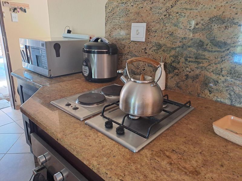 A kitchen workspace featuring granite countertops, a built-in oven, and a dual-hob setup with both electric and gas cooking options.