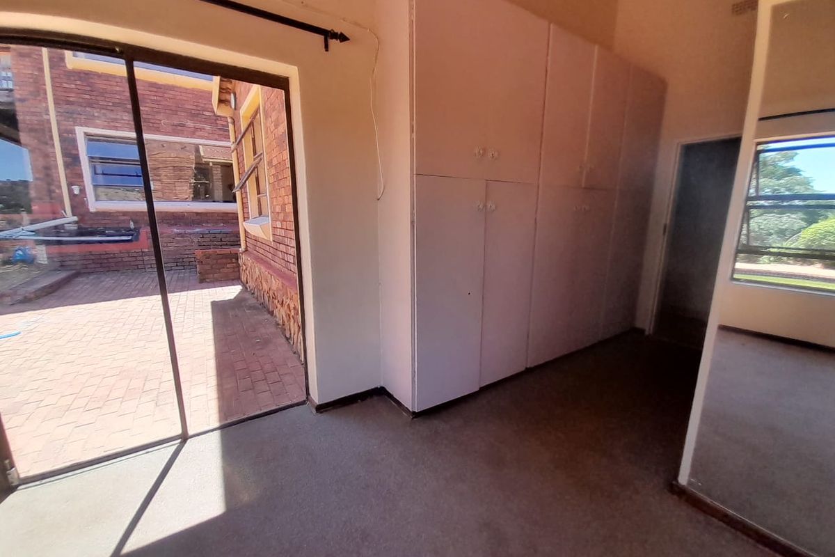 A spacious bedroom featuring built-in cupboards and a sliding glass door providing direct access to the outdoor patio area.