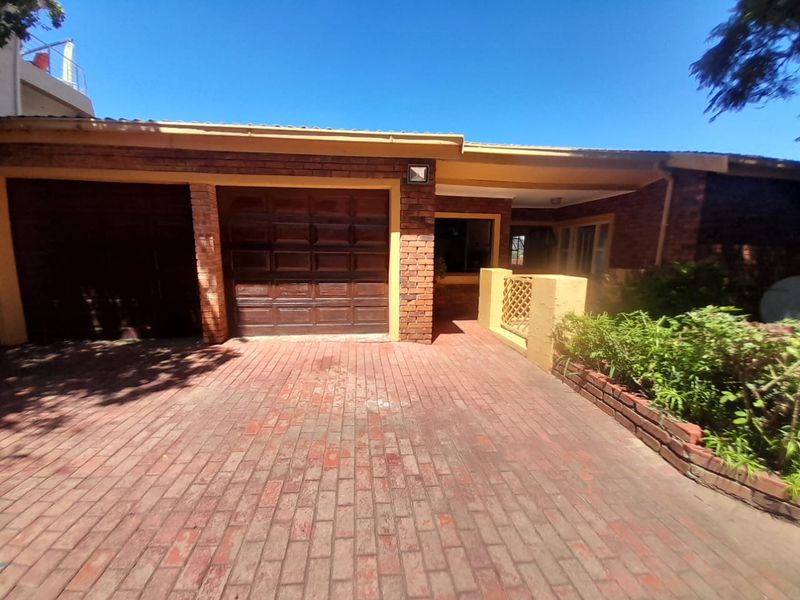 Front exterior view of the house featuring a brick driveway, double garage, and a covered entrance with established garden borders.