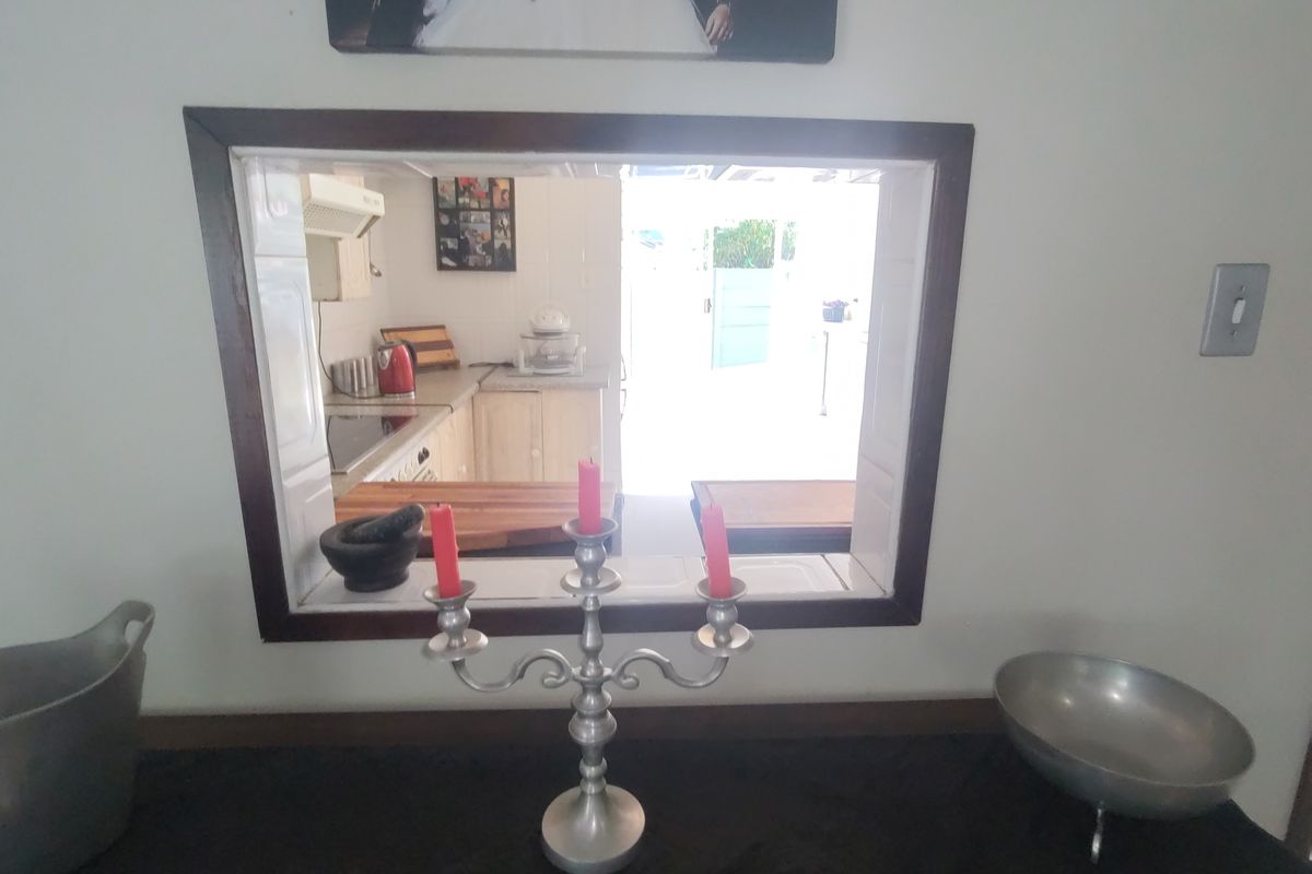 A view through a serving hatch into a kitchen area featuring built-in cabinetry and cooking appliances.