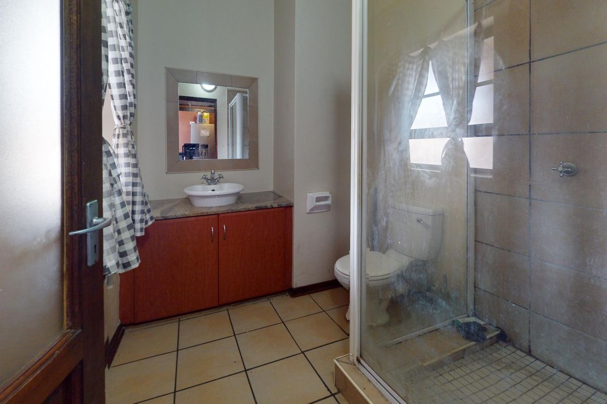 A functional bathroom featuring a vanity with a vessel sink, a toilet, and a glass-enclosed shower with tiled finishes.