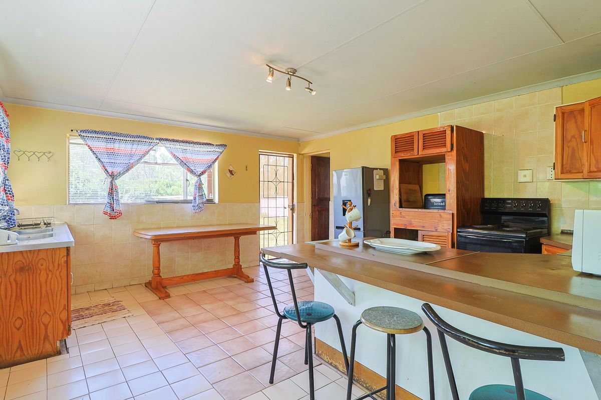 A functional kitchen featuring built-in wooden cabinetry, tiled flooring, and a breakfast counter, offering potential for modernization and aesthetic updates.