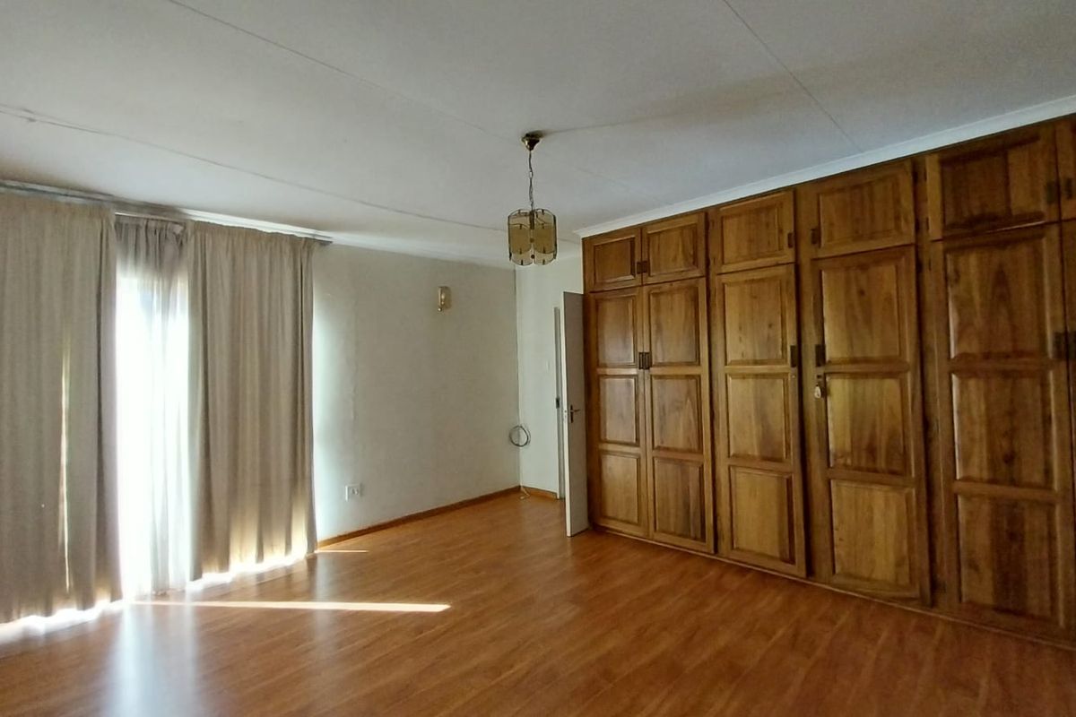 Spacious bedroom featuring extensive built-in wooden cabinetry and laminate flooring, offering ample storage and a bright, neutral atmosphere.