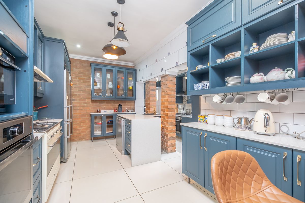 A well-appointed kitchen featuring blue cabinetry, stone countertops, exposed brick accents, and integrated appliances, offering a stylish and functional culinary space.