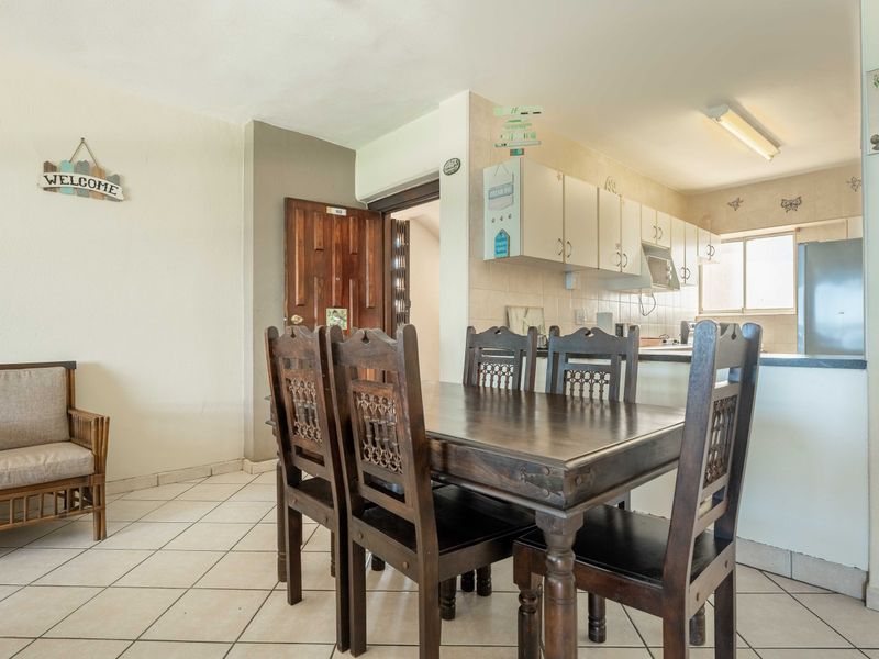 Open plan living and dining area featuring tiled flooring and a functional kitchen with built-in cabinetry and counter space.
