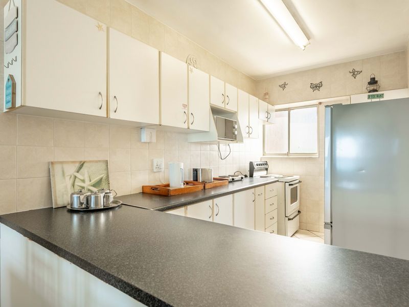 A functional kitchen featuring laminate countertops, ample built-in cabinetry, tiled backsplash, and a freestanding oven, offering a practical layout for daily meal preparation.