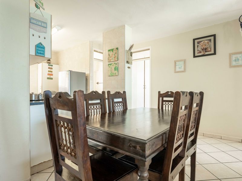 Open plan dining area adjacent to a functional kitchen with tiled flooring and neutral wall finishes.