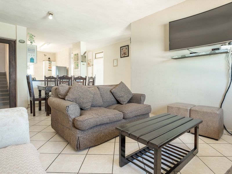 Open-plan living and dining area featuring tiled flooring and an adjacent kitchen space, providing a functional layout for daily living.
