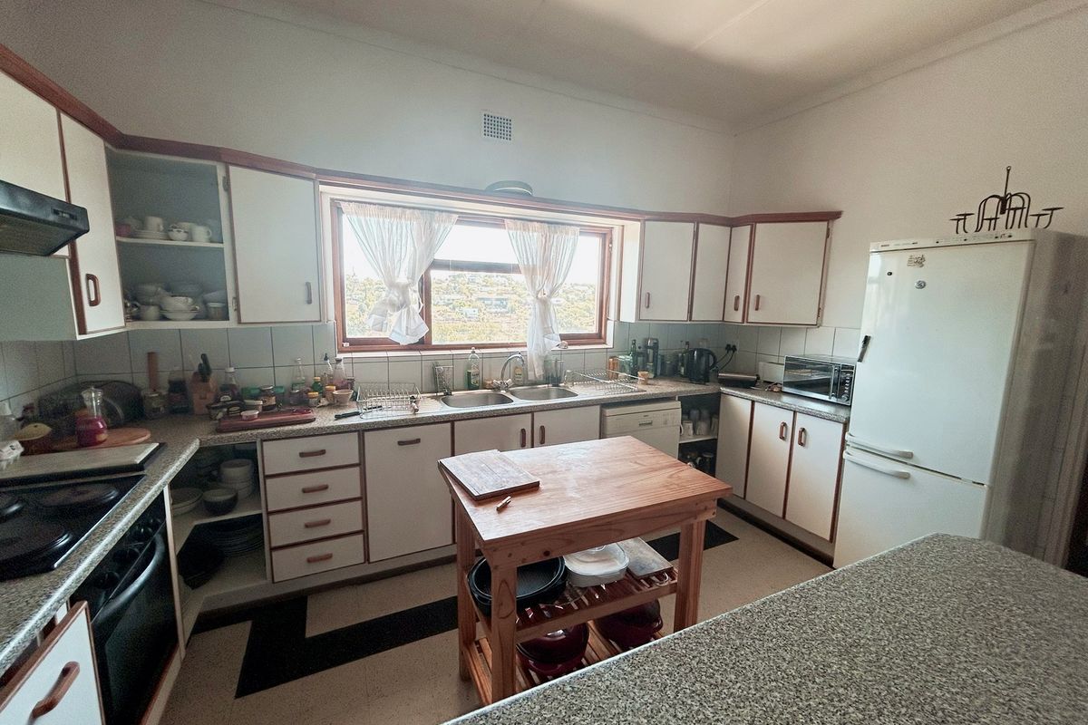 A functional kitchen featuring built-in cabinetry, double basin sink, and integrated appliances, offering a practical layout with potential for modern cosmetic updates.