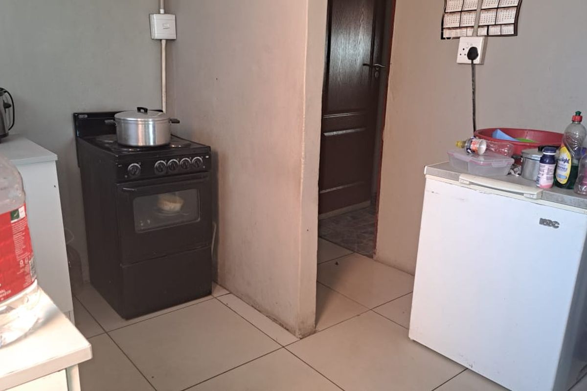 A functional kitchen area featuring tiled flooring, a freestanding stove, and basic cabinetry, providing a practical space for meal preparation.