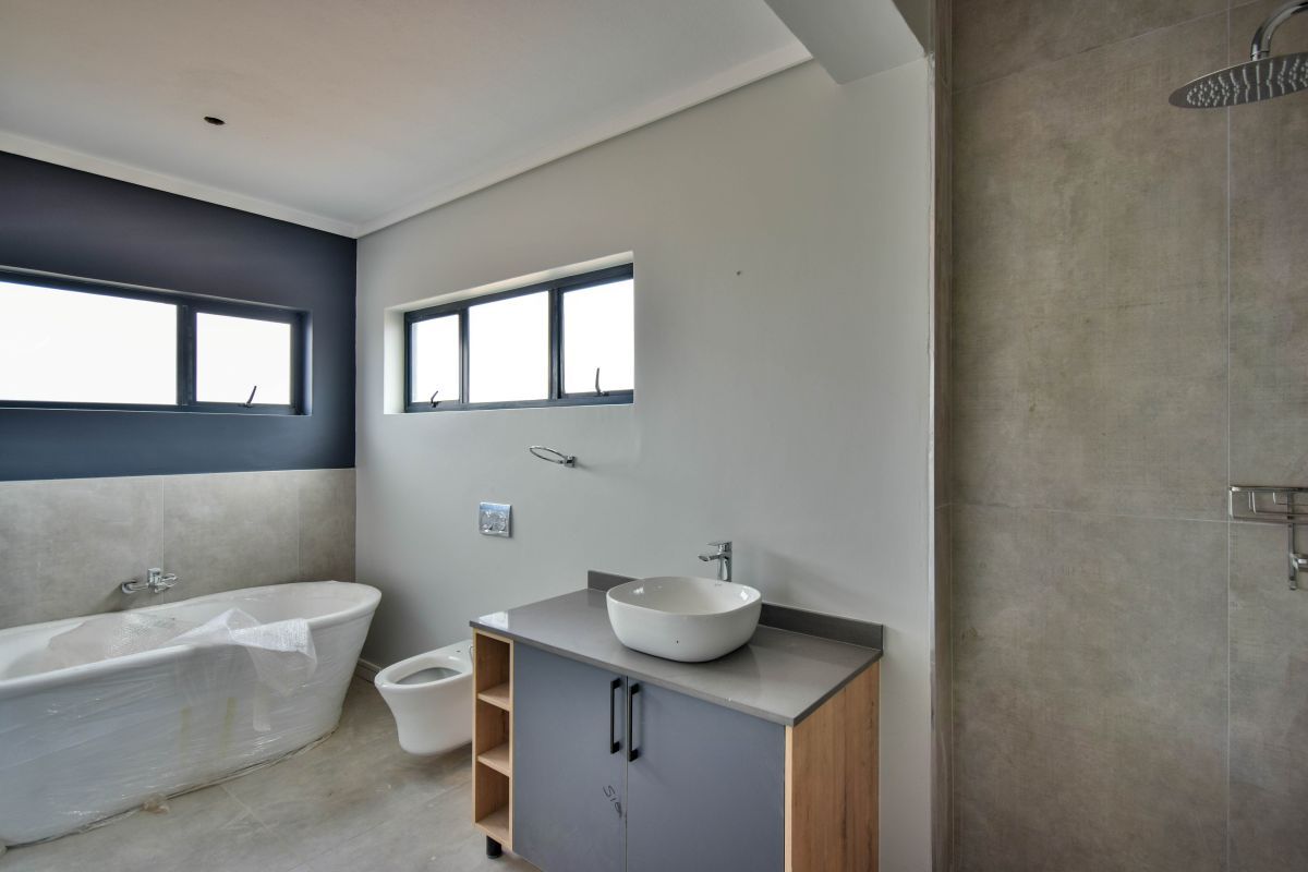 Modern bathroom featuring a freestanding bathtub, a contemporary vanity with a vessel sink, and a walk-in shower with large-format grey tiling.