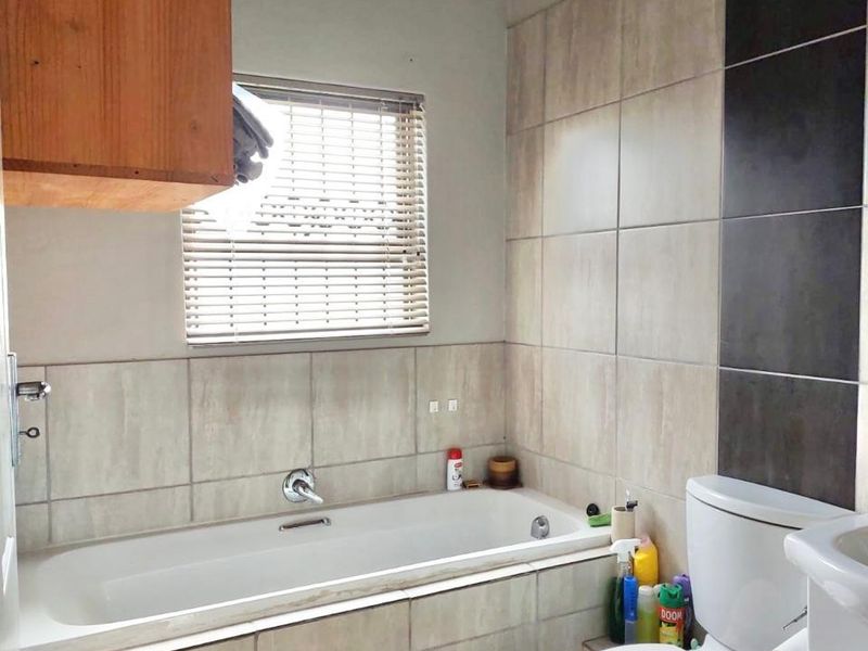 A functional bathroom featuring a built-in bathtub, tiled wall accents, and a standard toilet, offering a neutral base for potential cosmetic updates.