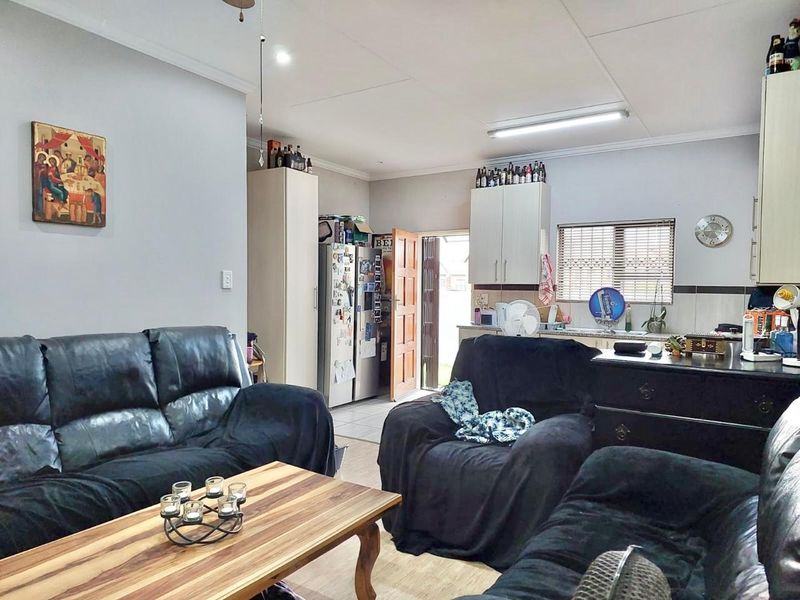 Open plan living and kitchen area featuring laminate flooring, functional cabinetry, and direct access to the exterior via a security gate.