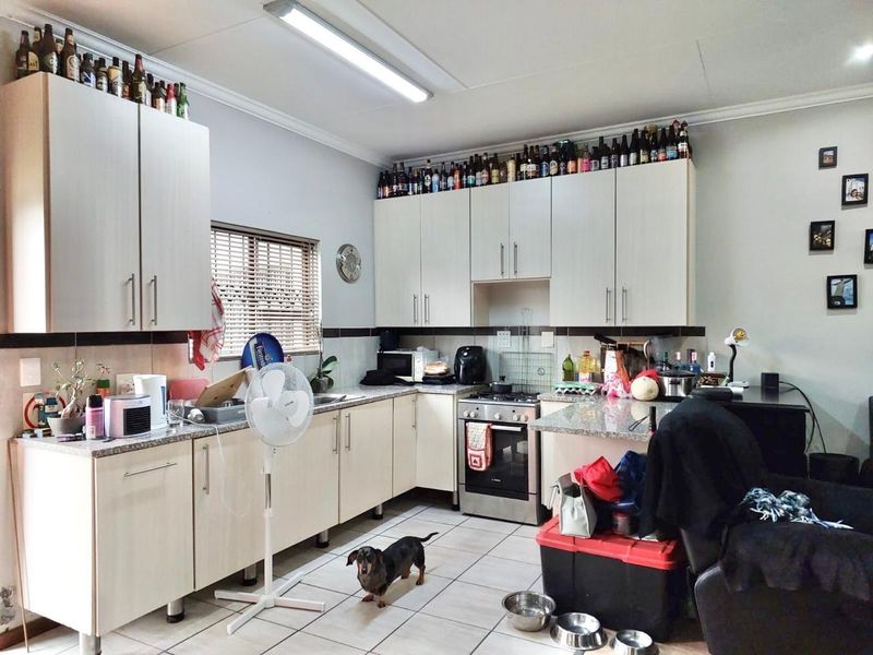 A functional kitchen featuring light-toned cabinetry, granite-look laminate countertops, a built-in oven and hob, and tiled backsplash with neutral floor tiles.
