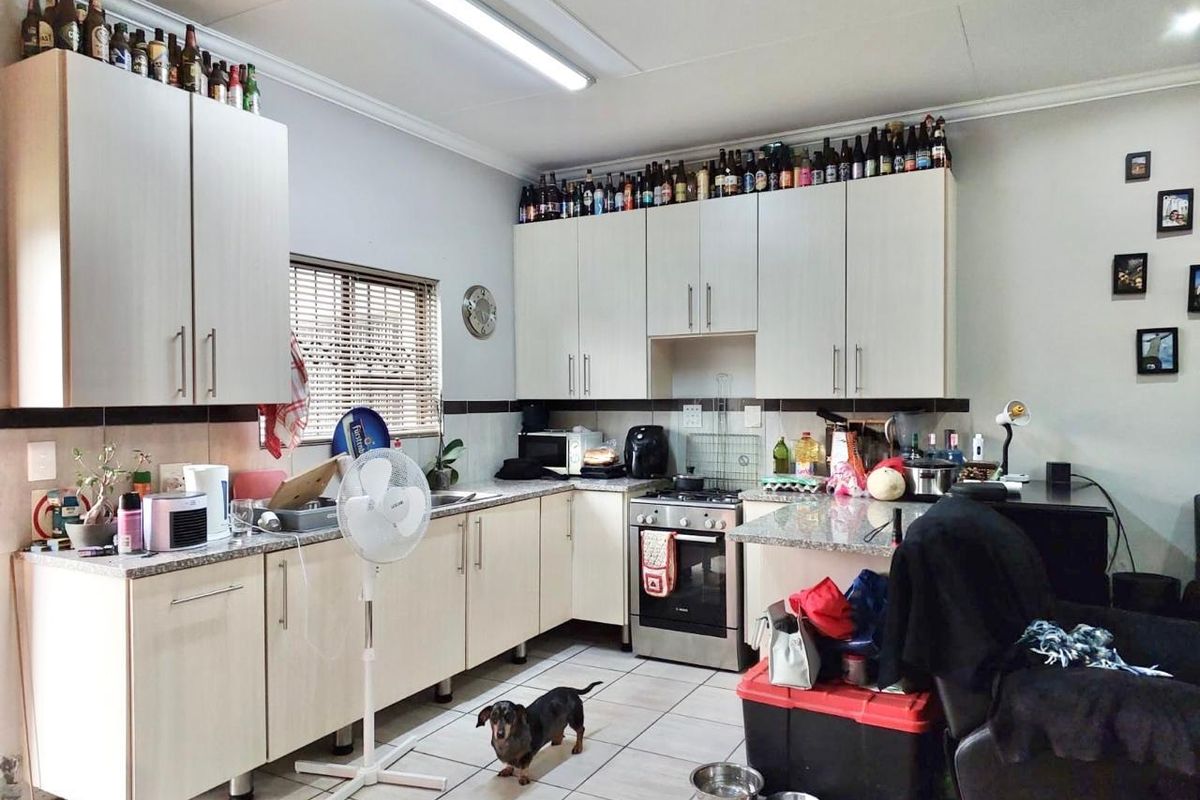 A functional kitchen featuring light-toned cabinetry, granite-look laminate countertops, a built-in oven and hob, and tiled backsplash with neutral floor tiles.