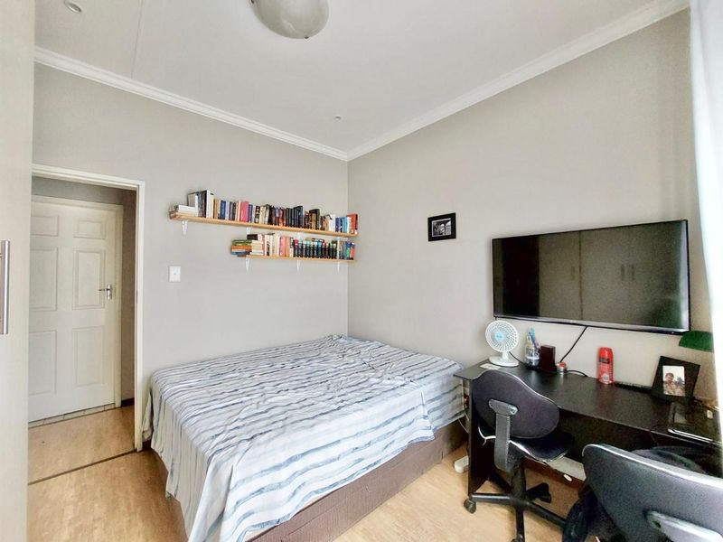 A functional bedroom featuring laminate flooring, neutral wall tones, and coving detail, providing a comfortable and versatile living space.