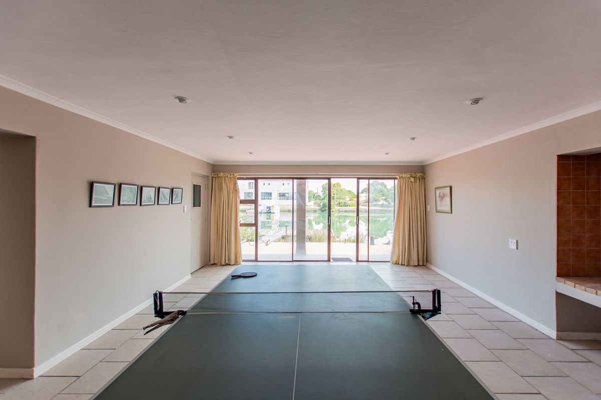 Spacious living area featuring tiled flooring, recessed lighting, and large sliding glass doors providing direct access to the outdoor area and water views.