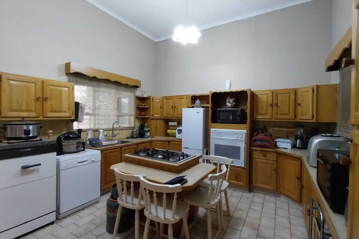 A spacious kitchen featuring traditional wooden cabinetry, a central island with a built-in gas hob, and tiled flooring.