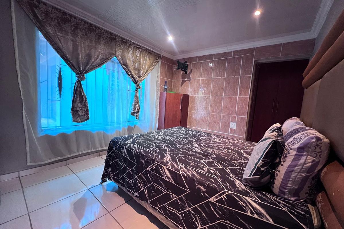 A bedroom featuring tiled flooring, a tiled accent wall, recessed lighting, and built-in storage, with security bars on the window.