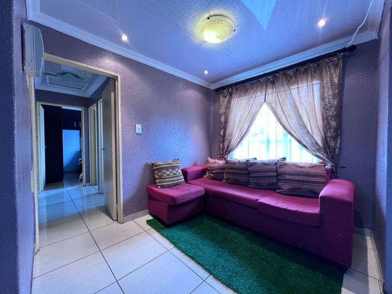 A living room featuring tiled flooring, ceiling cornicing, and a combination of flush mount and recessed lighting.