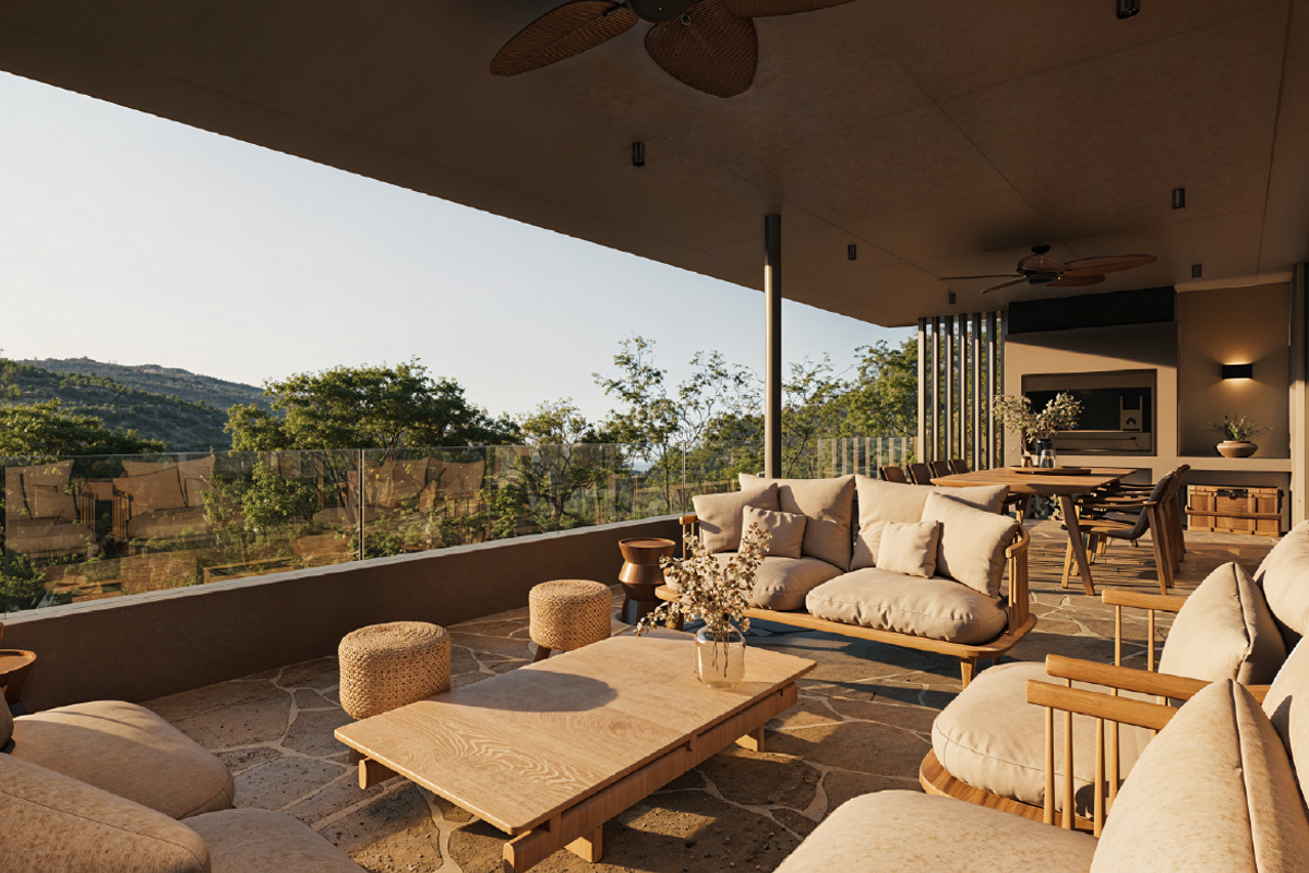 Spacious covered patio featuring stone flooring, a glass balustrade, built-in fireplace, and scenic elevated views of the surrounding landscape.