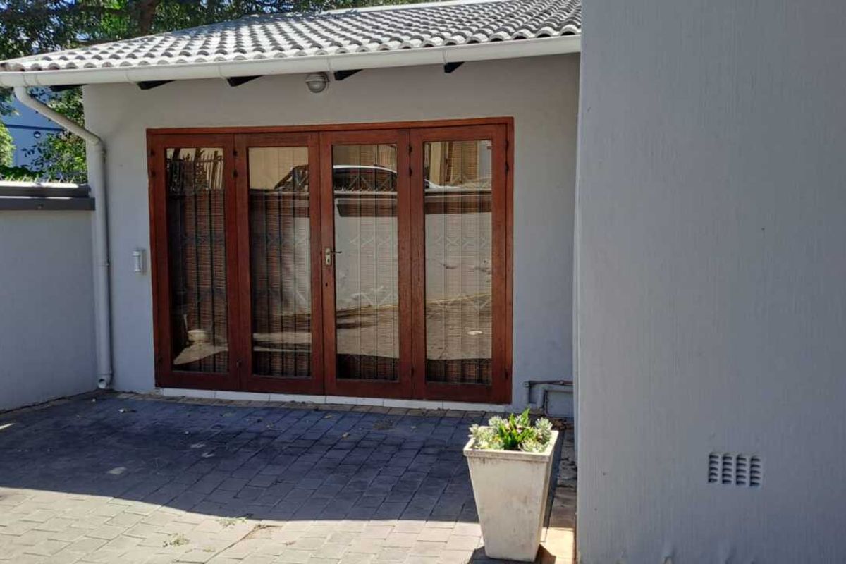 A private rear patio area featuring paved flooring and timber-framed folding glass doors, providing a seamless transition between indoor and outdoor living spaces.