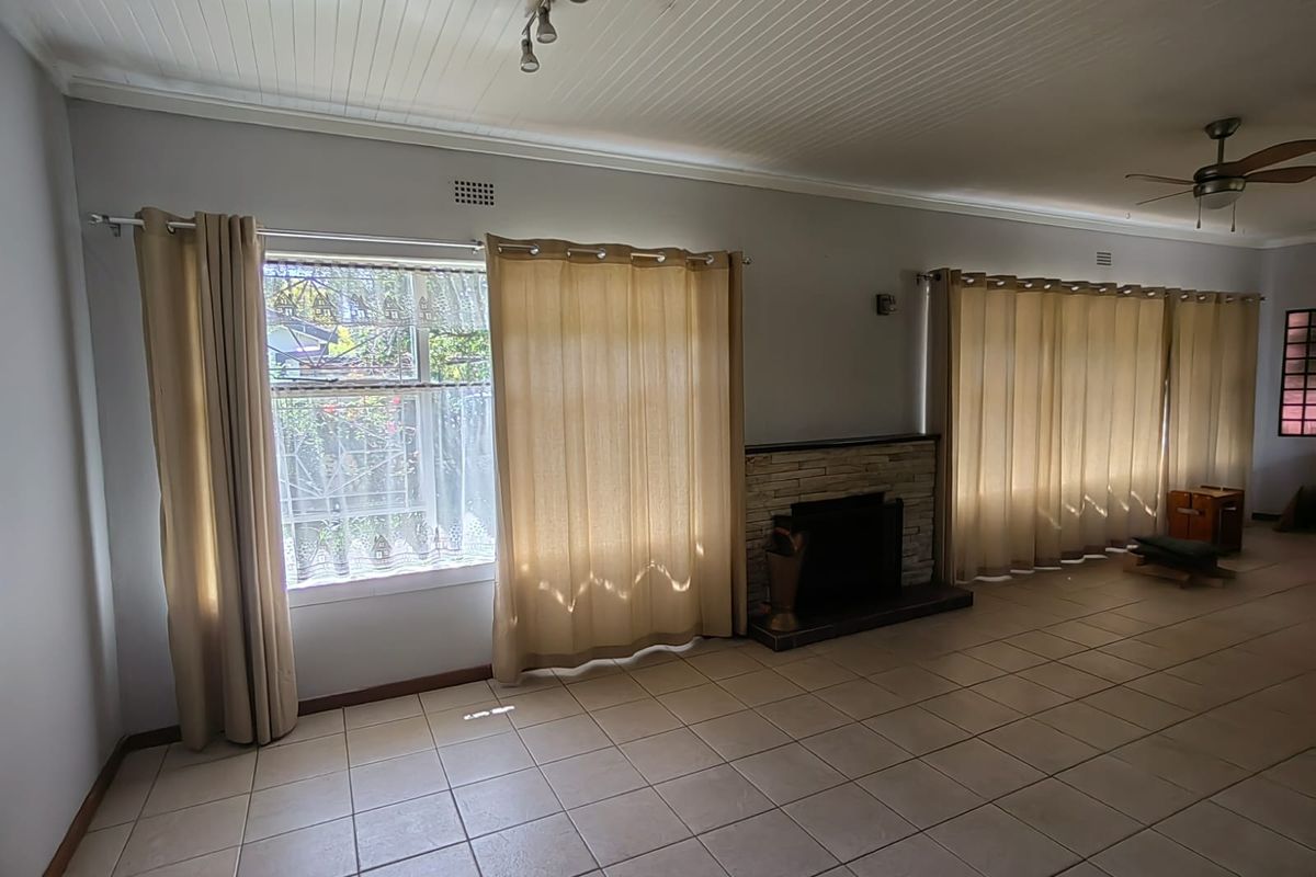 Spacious living room featuring tiled flooring, a stone fireplace, and a beadboard ceiling, offering a bright and open layout.