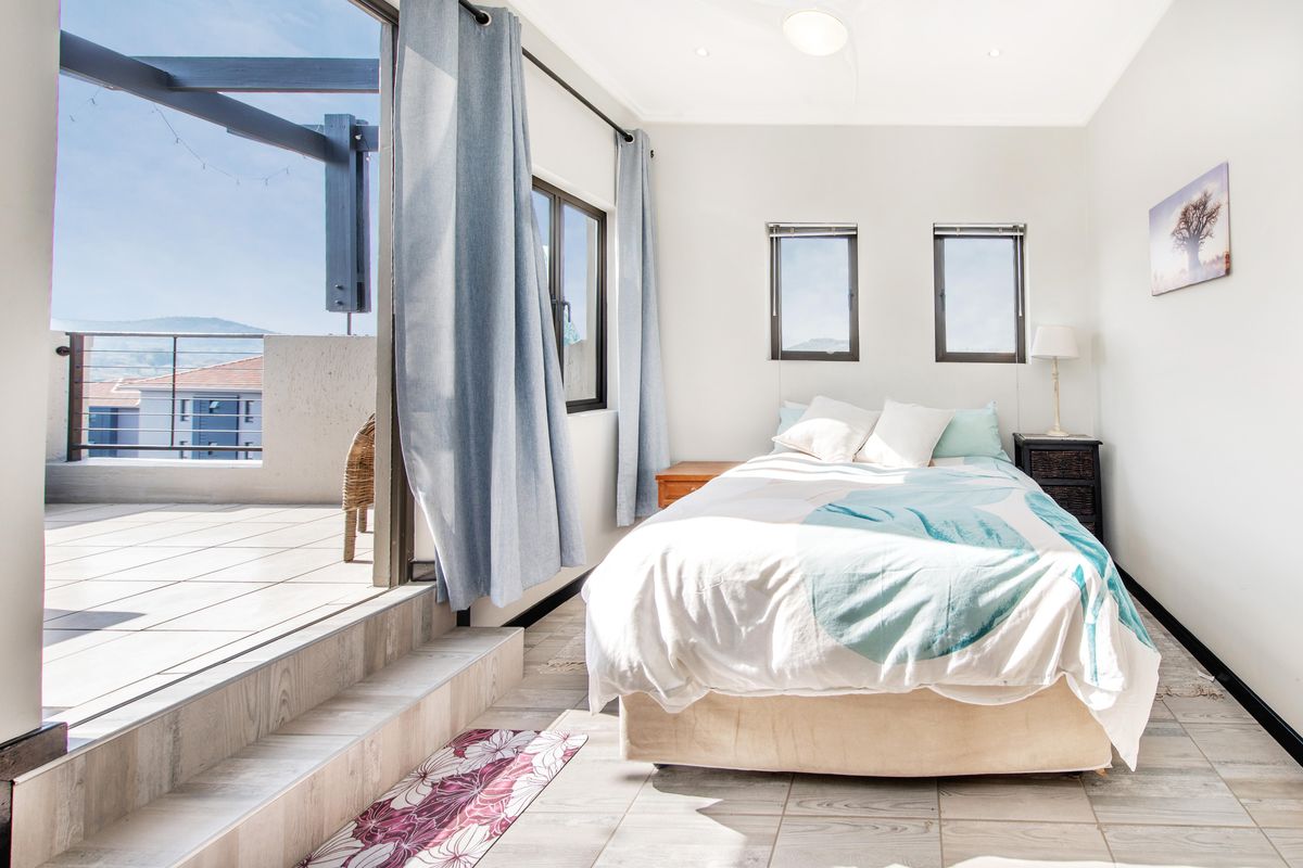 Bright bedroom featuring tiled flooring, recessed lighting, and direct access to a private balcony through large sliding glass doors.