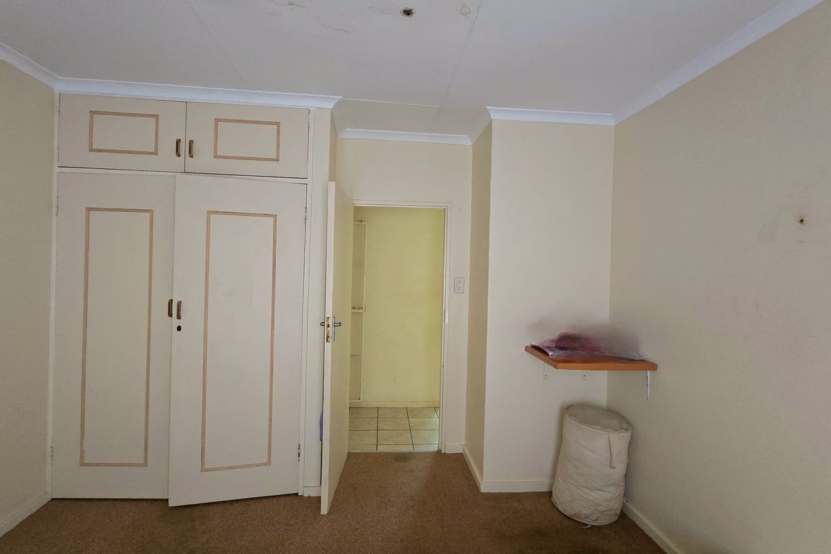 A vacant bedroom featuring built-in cupboards, carpet flooring, and coving, requiring cosmetic updates to improve its overall condition and appeal.