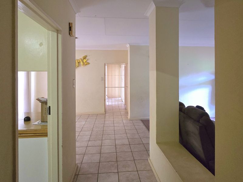 A tiled hallway connecting multiple living areas, featuring neutral wall tones and coved ceiling cornices, providing a functional transition space within the home.