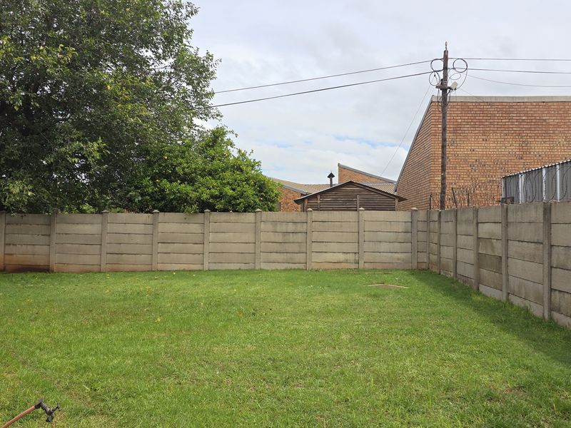 A private rear garden featuring a level lawn area enclosed by precast concrete boundary walls.