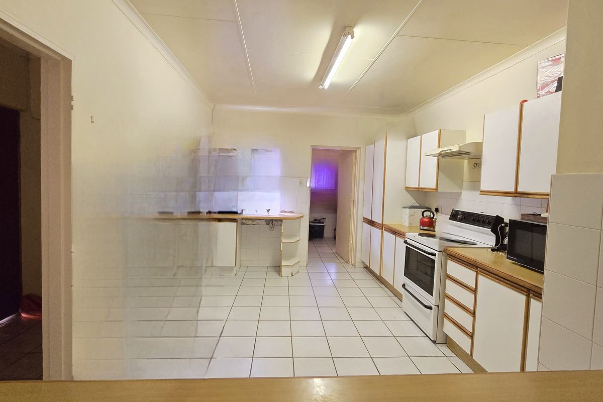 A functional kitchen featuring tiled flooring, built-in cabinetry, and a freestanding stove, offering a dated layout ready for modernization.