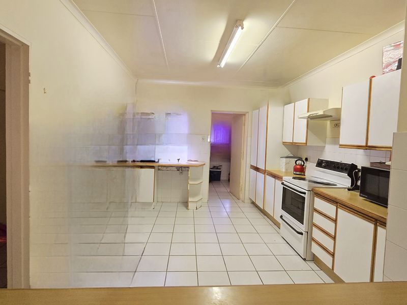 A functional kitchen featuring tiled flooring, built-in cabinetry, and a freestanding stove, offering a dated layout ready for modernization.