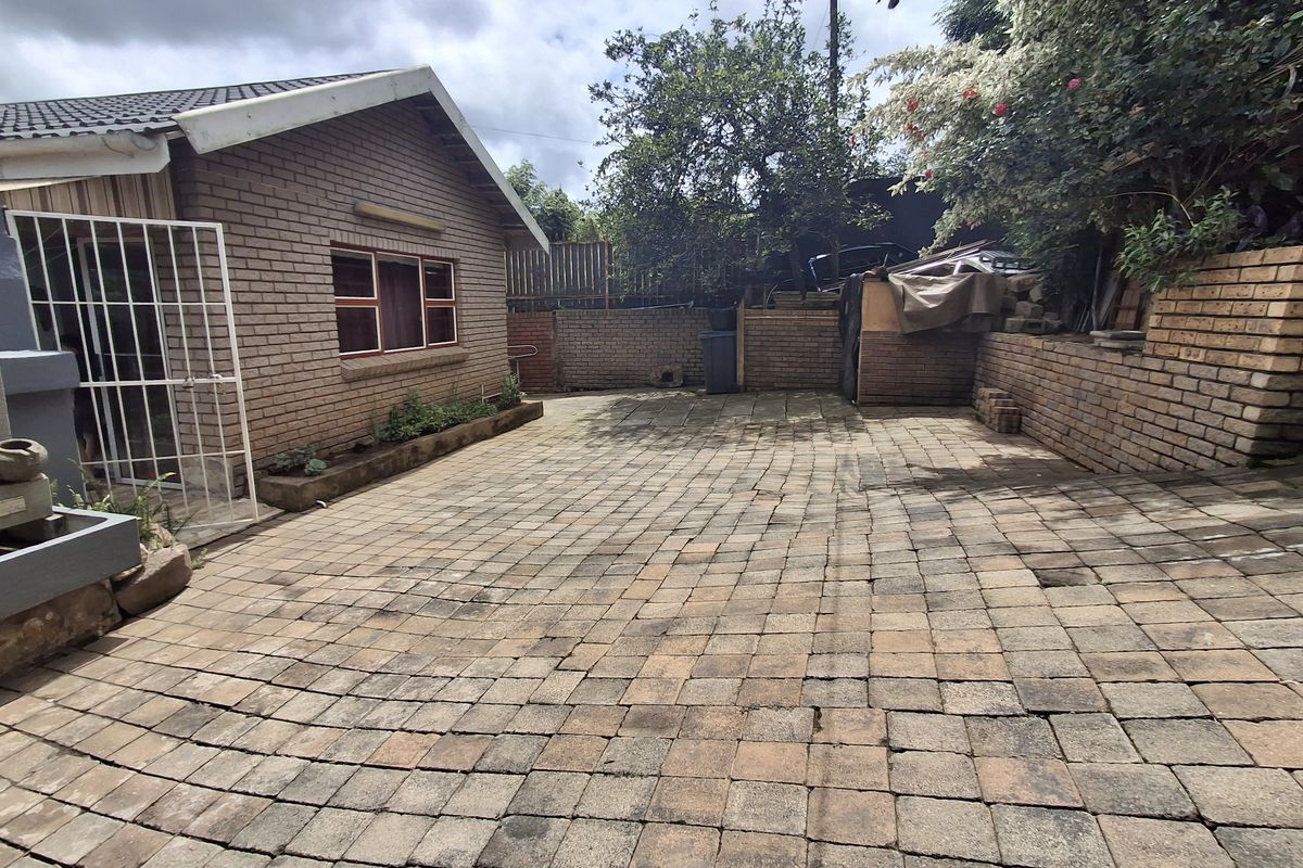 A paved rear courtyard area featuring brick retaining walls and a brick building facade, offering a functional outdoor space with potential for landscaping.