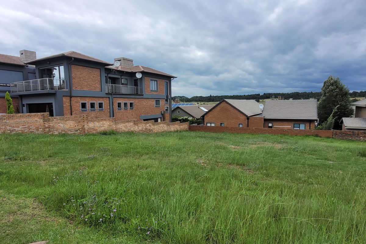 A vacant residential plot featuring a grass lawn and brick boundary walls, situated in a developed neighborhood with surrounding residential properties.