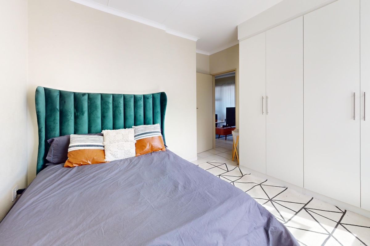 A well-maintained bedroom featuring floor-to-ceiling built-in cupboards and neutral wall finishes.