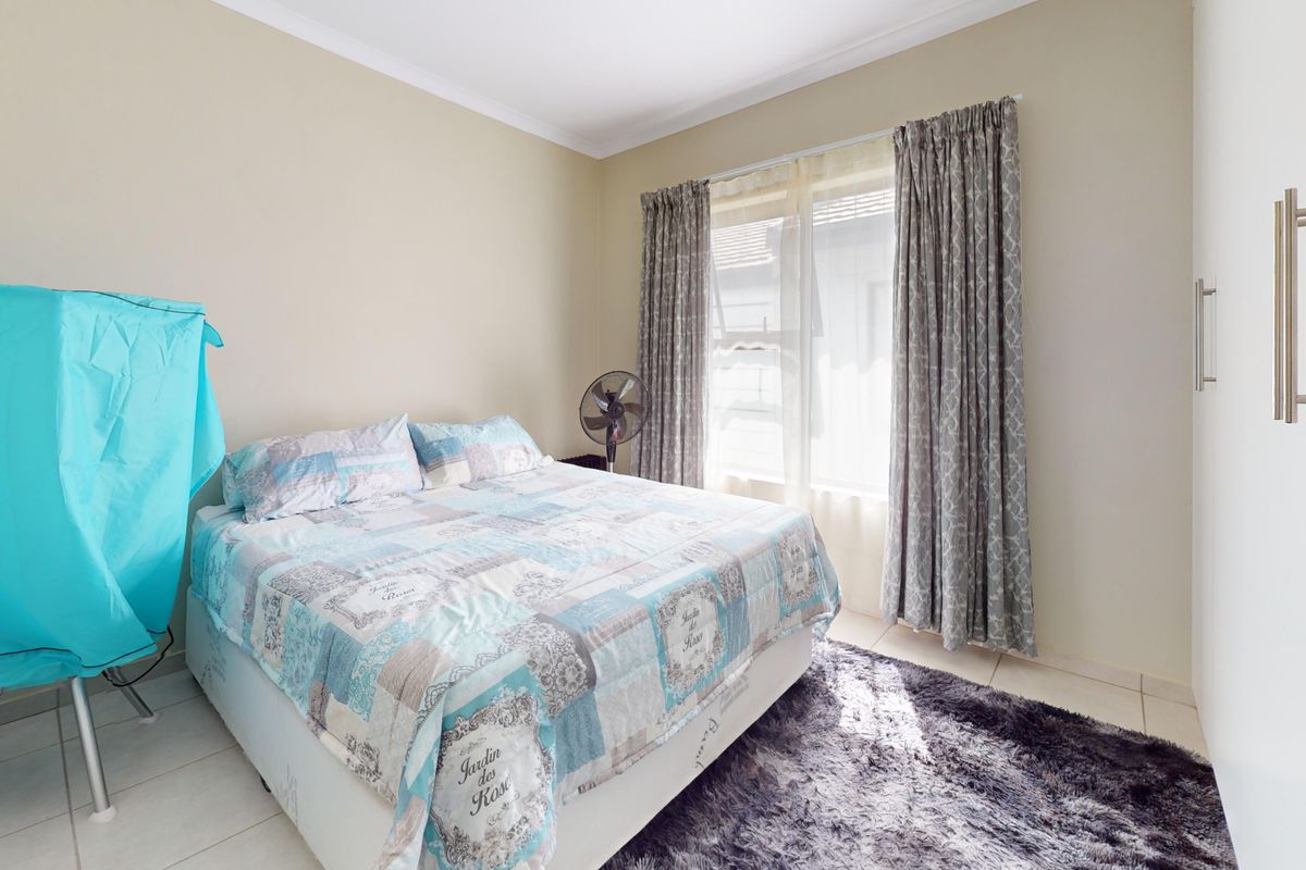 A bedroom featuring tiled flooring, a built-in wardrobe, and neutral wall finishes, providing a functional space with natural light.