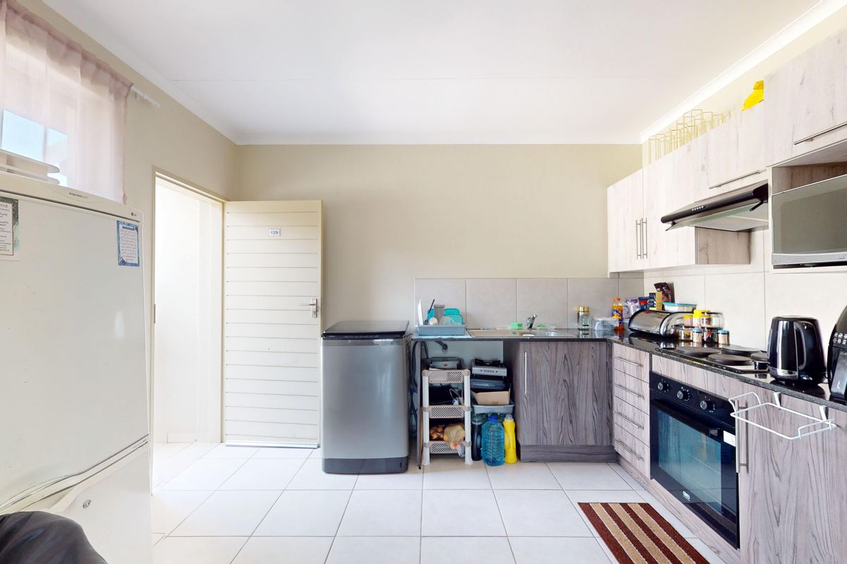 Functional kitchen featuring wood-look cabinetry, granite countertops, built-in oven, extractor fan, and integrated microwave with tiled flooring and backsplash.