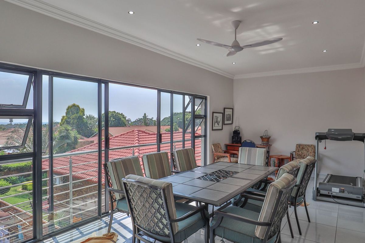 Spacious living area featuring large sliding glass doors, tiled flooring, recessed downlights, and a ceiling fan, offering a bright and airy atmosphere.