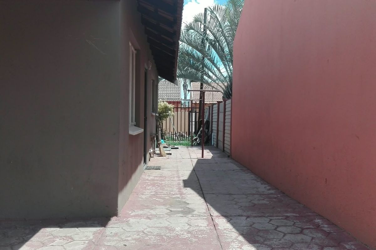 A narrow side passage featuring paved flooring and boundary walls, providing access to the rear of the property.