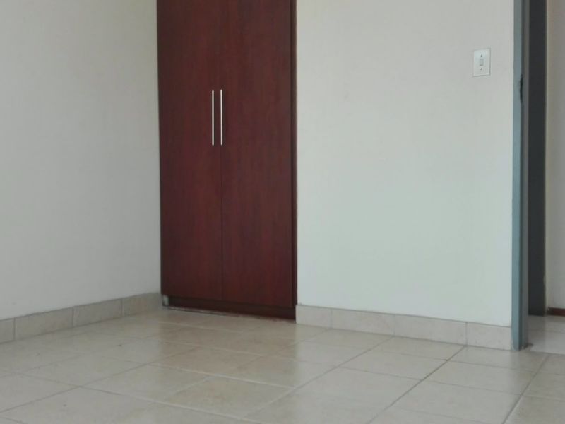 An empty bedroom featuring tiled flooring and a built-in wooden wardrobe with modern handles.