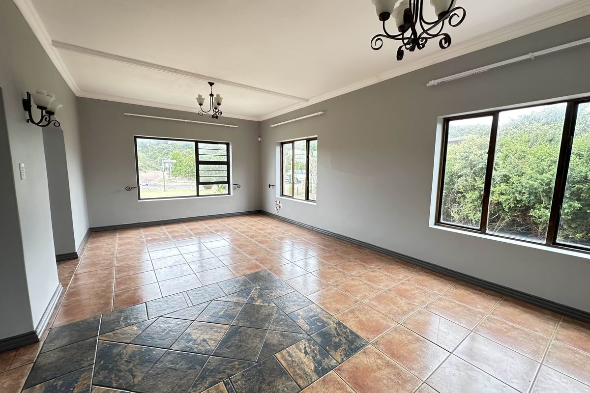Spacious living area featuring large windows, tiled flooring with decorative inlay, and classic chandelier lighting fixtures.