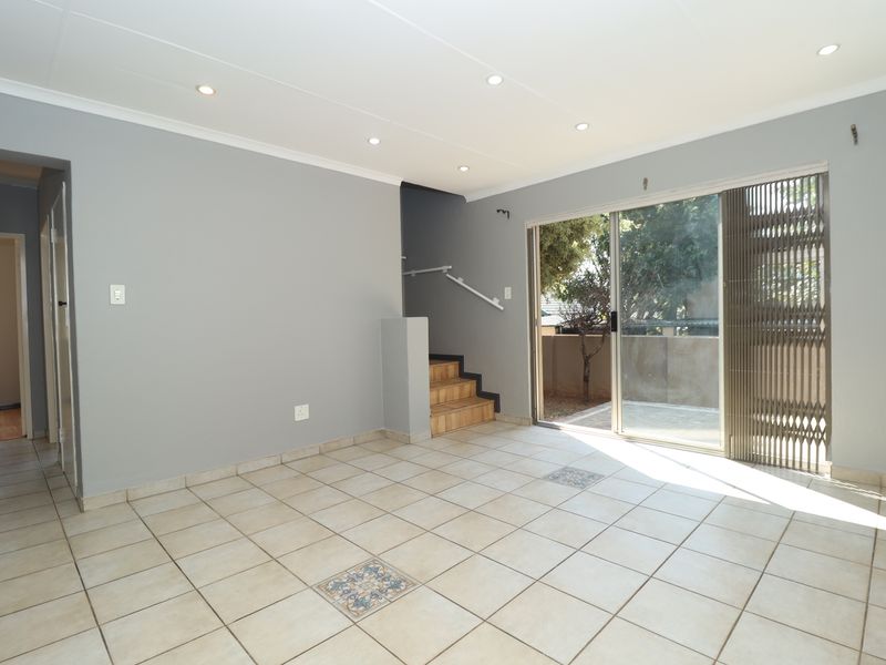 Spacious, light-filled living area featuring neutral tiled flooring, recessed lighting, and direct access to an outdoor patio through a sliding glass door.