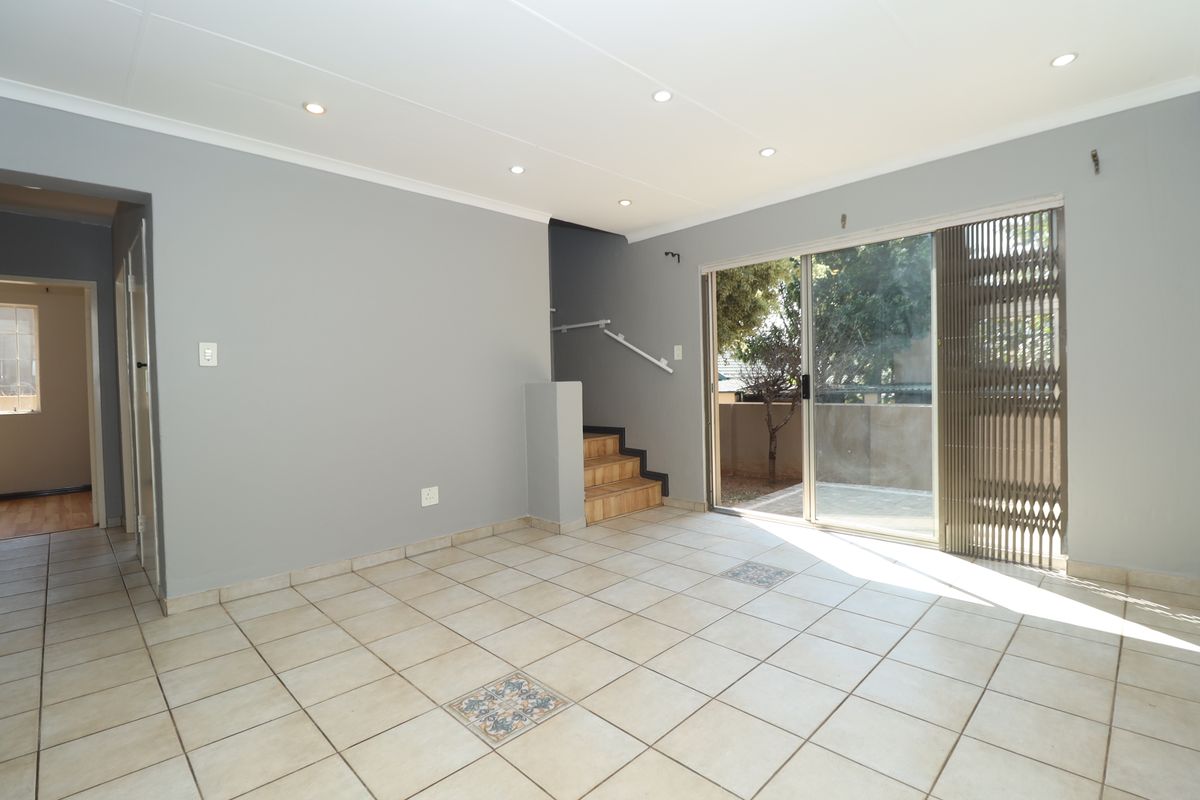 Spacious, light-filled living area featuring neutral tiled flooring, recessed lighting, and direct access to an outdoor patio through a sliding glass door.