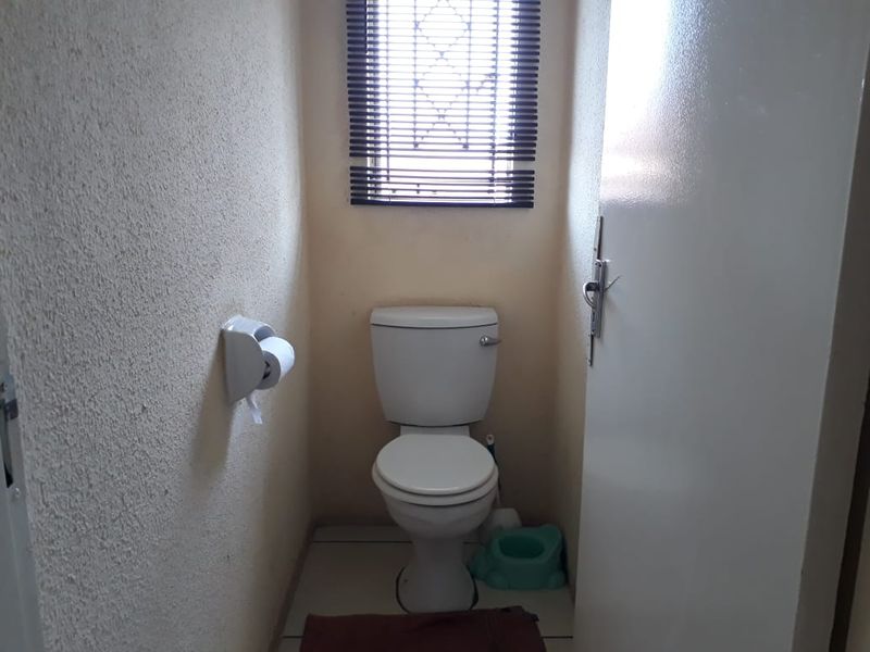 A compact, functional bathroom featuring a standard toilet, tiled flooring, and textured wall finishes.