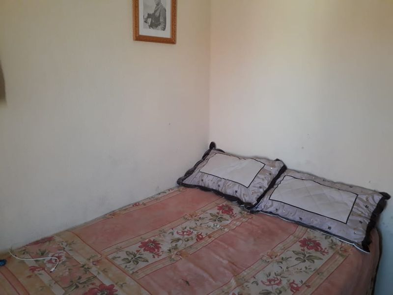 A compact bedroom space featuring plain wall finishes, suitable for modernization and aesthetic improvement.