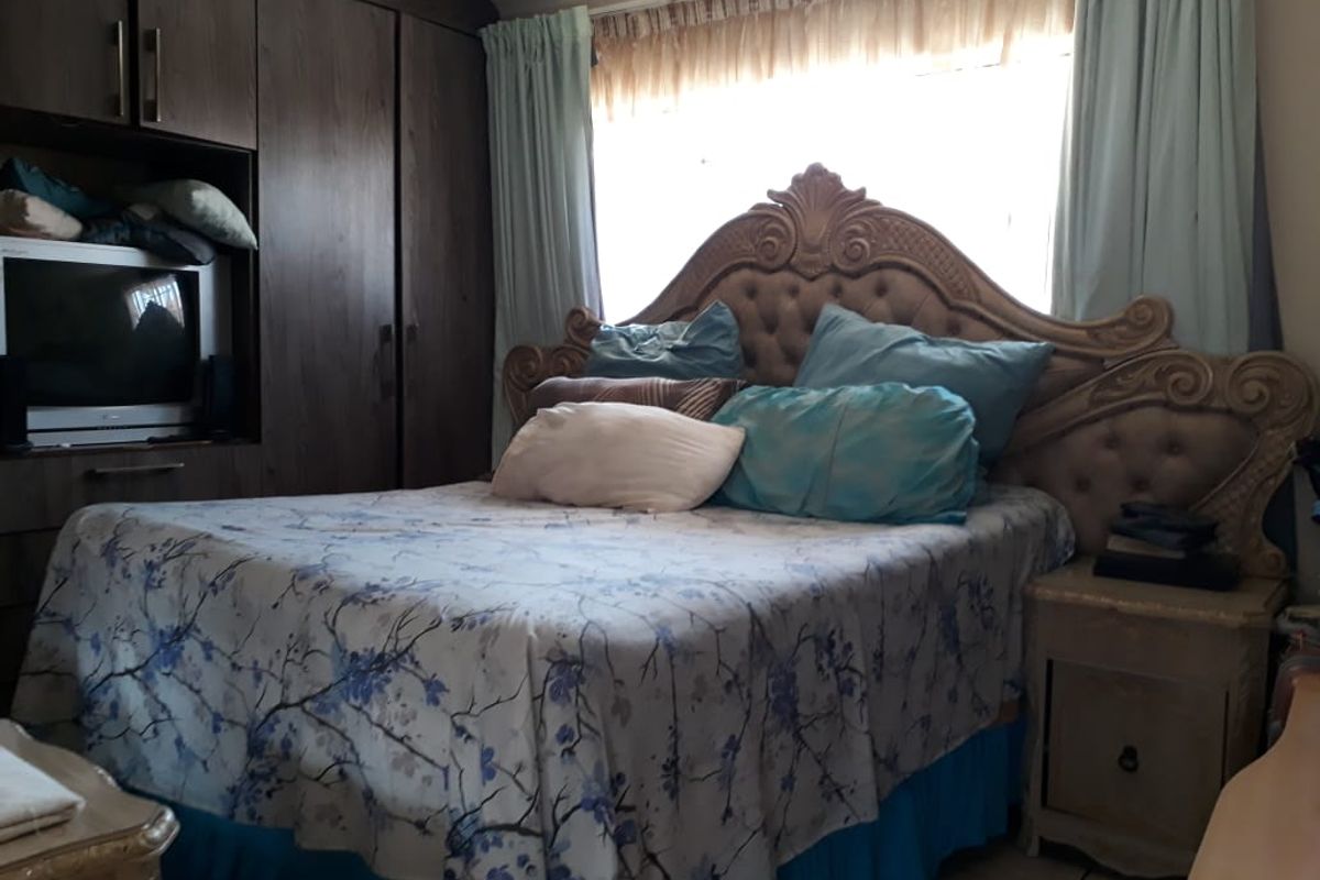A bedroom featuring built-in dark wood cabinetry and a large window with curtains.